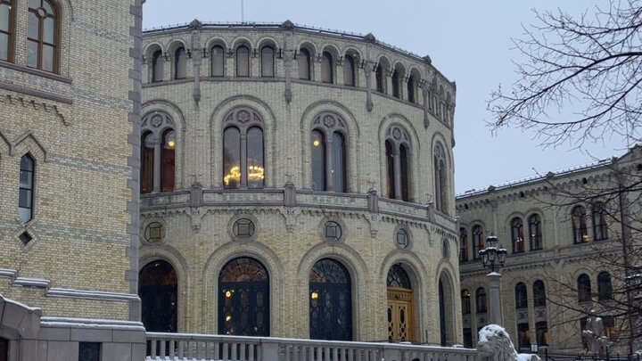 Foto av Stortingsbygningen, litt av ein løvestatue med snø på.
