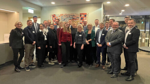 Foto av 22 personar som står i eit kontorbygg. På bildet er Sunnhordlandsrådet og Hordalandsbenken anno 2026